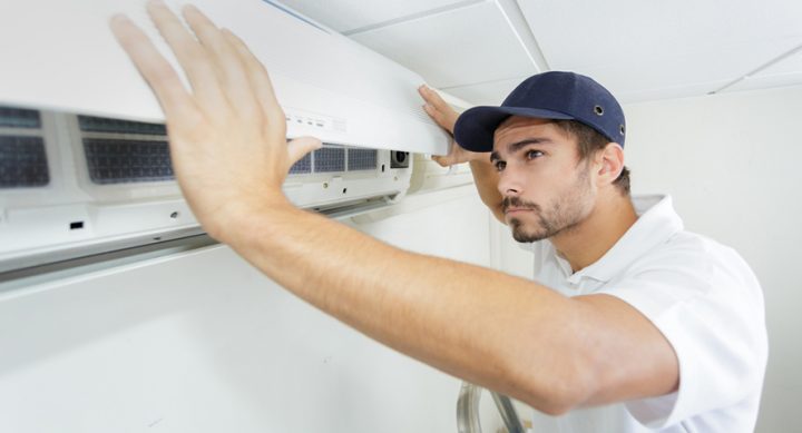 Making Your Aircon Cheaper A man fixing the aircon