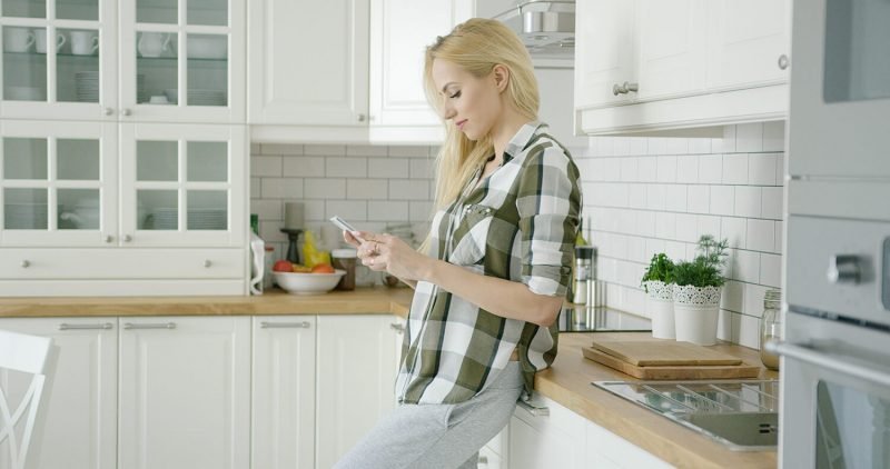 A woman using her cellphone on the kitchen