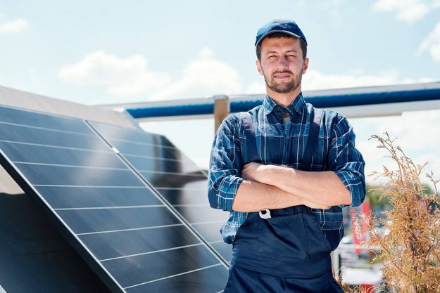 A man standing beside the solar panel