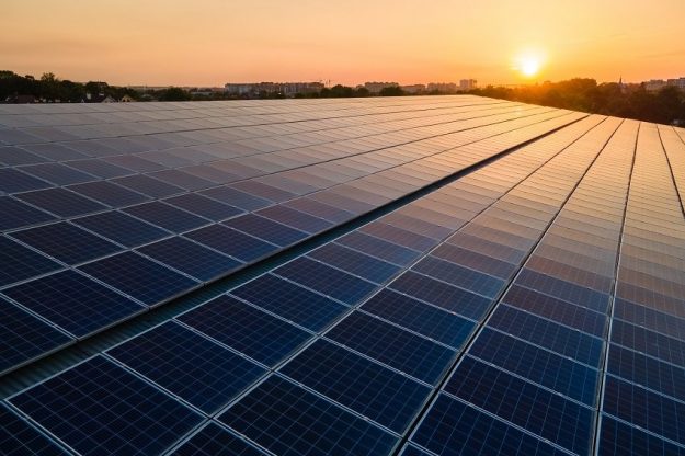 Blue photovoltaic solar panels mounted on building roof for producing clean ecological electricity at sunset. Production of renewable energy concept. solar panels on roof