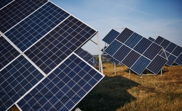 Field with solar batteries at sunny daytime. Conception of ecology and fuel solar farm on field