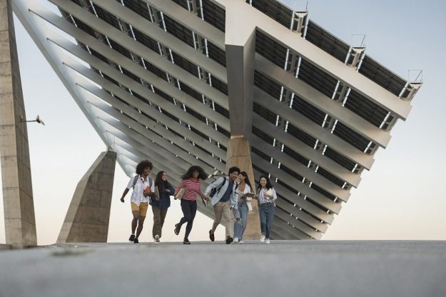 Group of students running underneath a modern solar panel struct