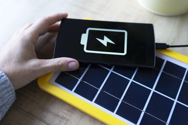 Renewable energy technology, solar panel charging a mobile phone battery Renewable energy technology, solar panel charging a mobile phone battery